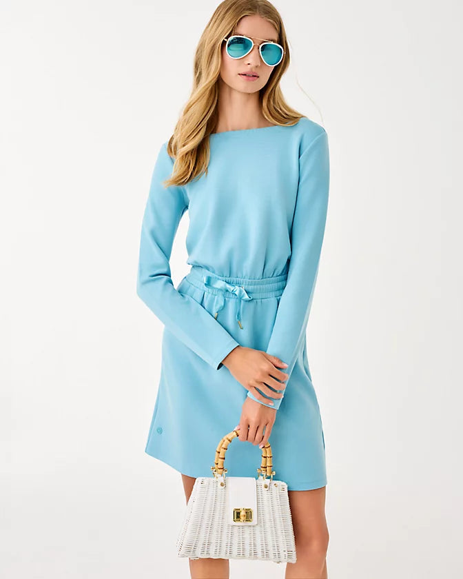 Woman wearing a light blue dress holding a white handbag against a white background